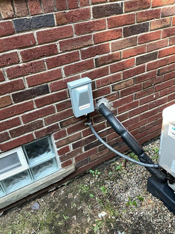 Completed comprehensive Gold AC inspection on a 4-year-old residential air conditioning system with outdoor condensing unit and basement-located air handler. Performed thorough visual assessment of exterior condenser unit positioned on concrete pad, verifying proper installation, clearances, and physical condition of cabinet and coil fins. Inspected electrical disconnect box and associated conduit connections mounted on exterior wall for secure mounting and proper weatherproofing. Evaluated refrigerant lines, electrical connections, and overall system operation. Unit found to be in good working condition with no immediate service concerns identified. All components inspected and verified operational per manufacturer specifications and industry standards.
