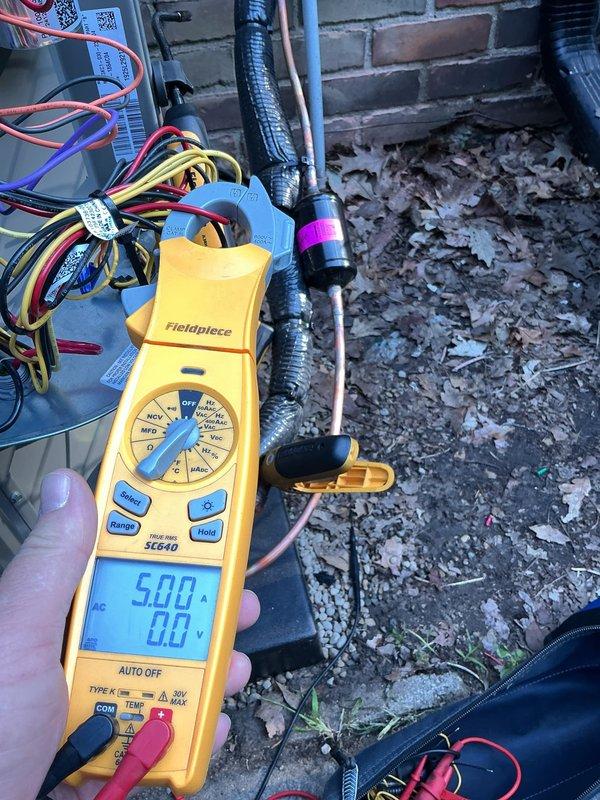 Returned to site to continue compressor diagnostics on outdoor HVAC unit. Performed electrical testing using digital multimeter and clamp meter to measure voltage and amperage at the condensing unit. Readings indicated 62.1 amps with voltage measurements taken at multiple points in the system. Inspected wiring harnesses, refrigerant line connections, and conduit routing. Documented findings with photos for further analysis and determination of compressor viability.