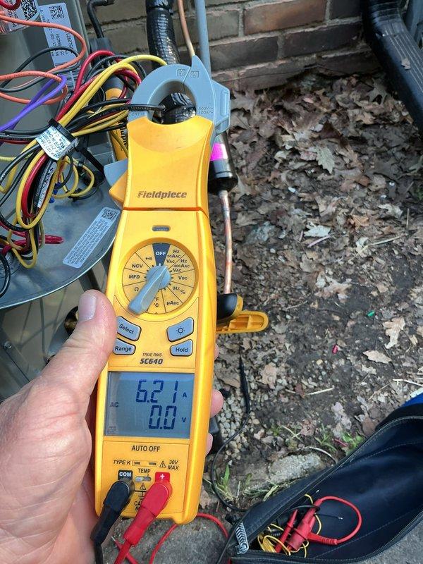 Returned to site to continue compressor diagnostics on outdoor HVAC unit. Performed electrical testing using digital multimeter and clamp meter to measure voltage and amperage at the condensing unit. Readings indicated 62.1 amps with voltage measurements taken at multiple points in the system. Inspected wiring harnesses, refrigerant line connections, and conduit routing. Documented findings with photos for further analysis and determination of compressor viability.