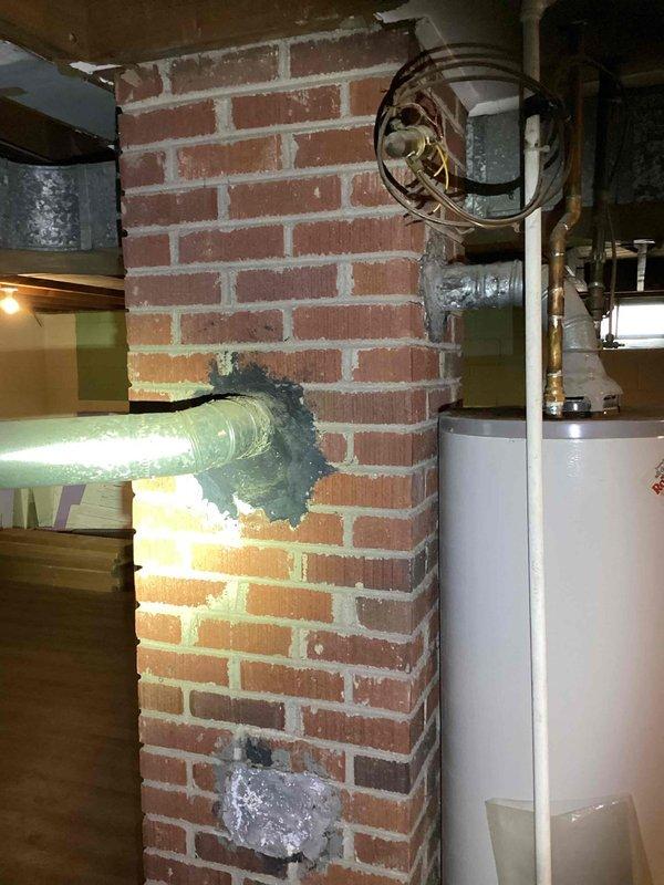 Conducted furnace replacement estimate for a 38-year-old heating unit located in an unfinished basement with exposed joists and concrete flooring. Documented existing equipment configuration, including proximity to water heater, copper plumbing lines, brick wall penetrations, and HVAC ductwork routing. Assessed basement access via wooden staircase and photographed mechanical room layout to determine optimal replacement equipment specifications and installation requirements.