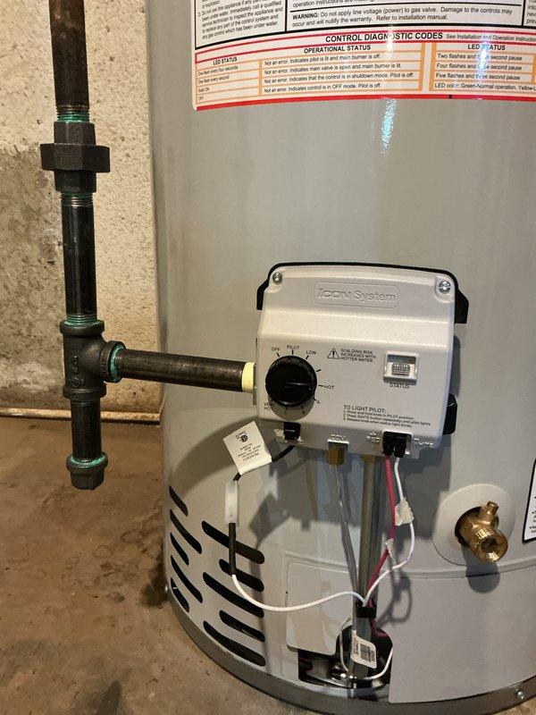Installed Zoen System electronic control module on Bradford White 50-gallon natural gas water heater. Connected control wiring and network port to enable smart monitoring and diagnostic capabilities. Verified all plumbing connections, including metal pipe unions and fittings on cold water supply line. Confirmed proper installation of drain pan beneath unit and tested brass valve operation. Documented water heater specifications and safety label information for service records.
