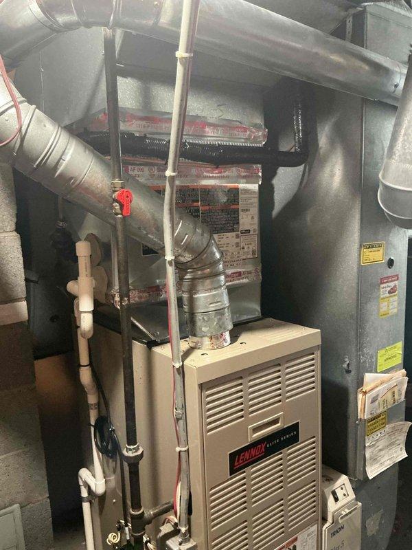 Completed installation of 2-ton air conditioning system with new evaporator coil connected to existing Lennox furnace in basement mechanical room. Installed outdoor condenser unit in rear yard on gravel pad with proper refrigerant line connections, performed system flush, and reconnected electrical service. Conducted startup procedures with manifold gauges to verify proper refrigerant charge, system pressures, and operational performance; all mechanical and electrical permits requested and system remeasured per specifications.