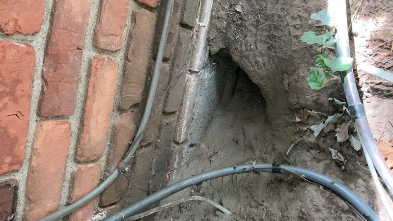 Responded to service call for air conditioning system not cooling adequately. Unit located in basement with outdoor components installed in foundation trench area. Inspected outdoor condenser unit and associated refrigerant lines, electrical conduits, and utility connections along building foundation. Evaluated system performance, checked refrigerant line insulation, and examined outdoor equipment installation in below-grade utility trench. Documented existing conditions of outdoor AC components and utility routing for further diagnostic assessment.