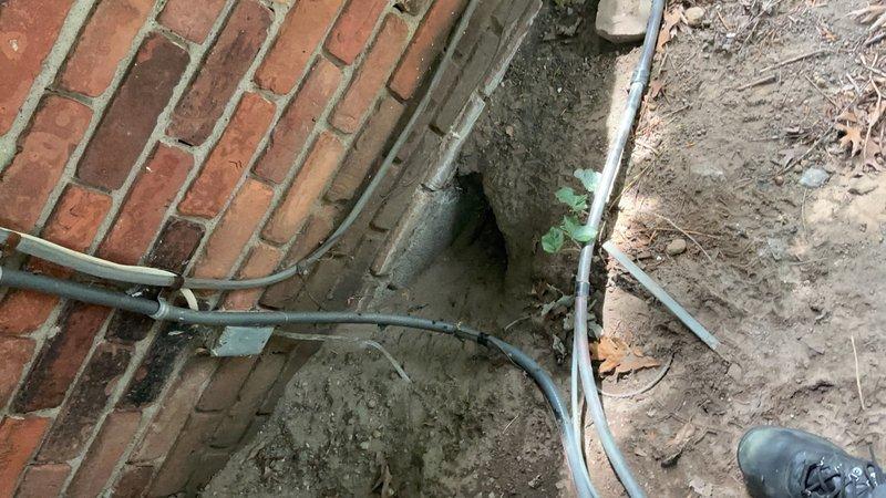 Responded to service call for air conditioning system not cooling adequately. Unit located in basement with outdoor components installed in foundation trench area. Inspected outdoor condenser unit and associated refrigerant lines, electrical conduits, and utility connections along building foundation. Evaluated system performance, checked refrigerant line insulation, and examined outdoor equipment installation in below-grade utility trench. Documented existing conditions of outdoor AC components and utility routing for further diagnostic assessment.