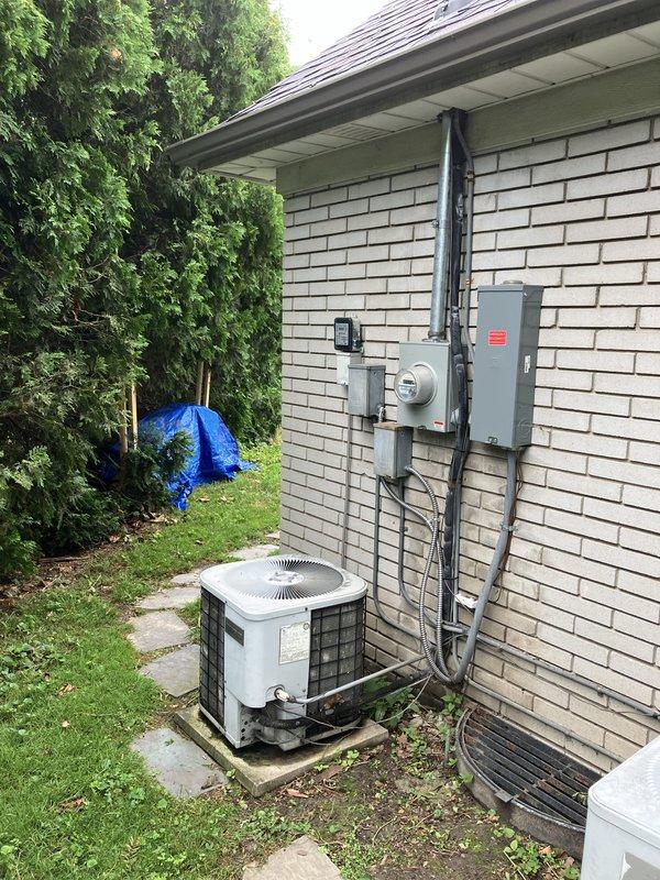 Conducted full system estimate for residential property with two aging outdoor condenser units that are failing to cool below 78 degrees. Performed visual inspection and documentation of both white-cased condenser units positioned on concrete pads against white brick exterior wall. Assessed existing electrical infrastructure including wall-mounted meter, panel box, and conduit routing. Evaluated unit placement, surrounding clearances, and existing concrete pad conditions. Photographed equipment configuration and site conditions to provide comprehensive replacement quote for dual HVAC system upgrade.
