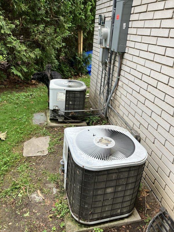 Conducted full system estimate for residential property with two aging outdoor condenser units that are failing to cool below 78 degrees. Performed visual inspection and documentation of both white-cased condenser units positioned on concrete pads against white brick exterior wall. Assessed existing electrical infrastructure including wall-mounted meter, panel box, and conduit routing. Evaluated unit placement, surrounding clearances, and existing concrete pad conditions. Photographed equipment configuration and site conditions to provide comprehensive replacement quote for dual HVAC system upgrade.