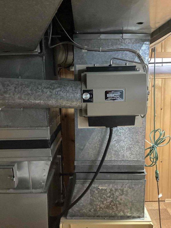 Conducted on-site evaluation of 40-year-old air conditioning system located at rear of property to provide replacement estimate. Assessed existing outdoor condensing unit and documented current equipment condition, including examination of indoor air handling components and ductwork system with integrated humidifier. Photographed existing HVAC infrastructure to support equipment sizing and replacement specifications for comprehensive system upgrade proposal.