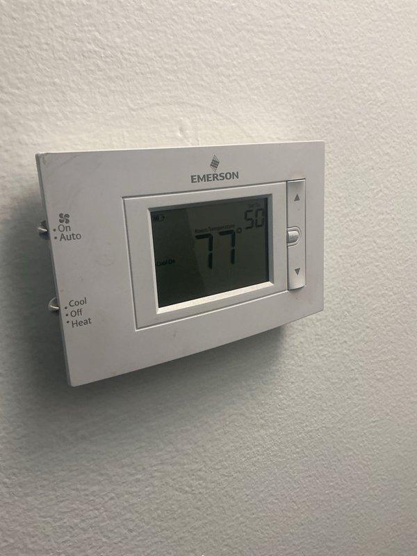 Responded to no cooling complaint on residential split system air conditioning unit. Upon arrival, found thermostat calling for cooling with indoor temperature reading 77°F and setpoint at 54°F, indicating system was running but not achieving temperature. Inspected furnace/air handler in basement and verified blower operation. Proceeded to outdoor condensing unit located behind residence and diagnosed complete refrigerant loss due to leak in system. System was unable to provide cooling capacity and required refrigerant recovery, leak detection, repair, and recharge to restore proper operation.