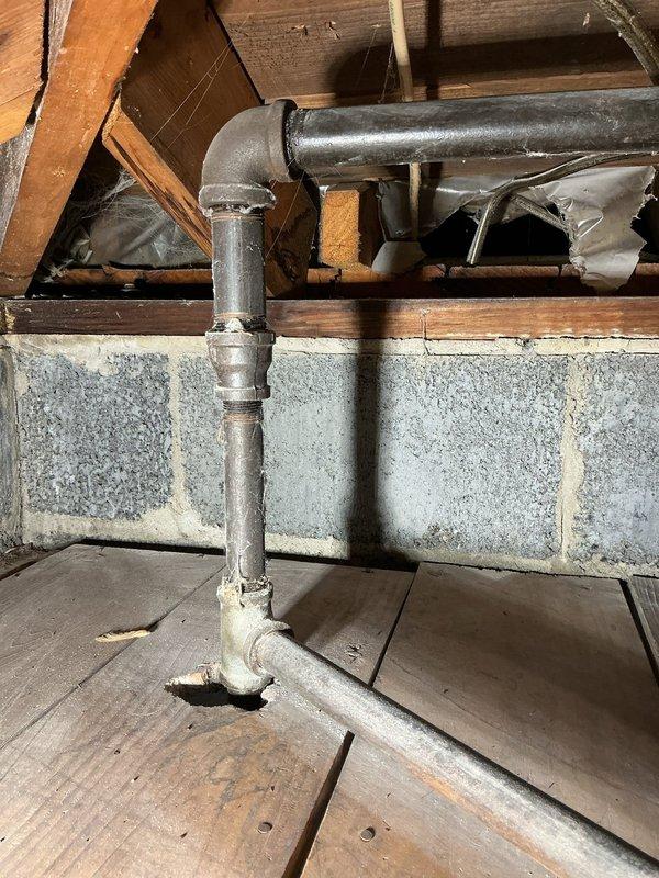 Completed gas line repair work at residential property with active construction in area. Inspected and serviced vertical gas piping system running along exterior corner of home, addressing rust staining and corrosion at lower connection point near valve assembly. Evaluated basement gas line configuration including aged galvanized piping with T-junction connections showing surface oxidation and dust accumulation. Verified proper mounting and support brackets on exterior PVC vent piping. Assessed structural clearances around gas lines passing through floor joists in crawl space area. All work performed in accordance with applicable gas fitting codes and safety standards.