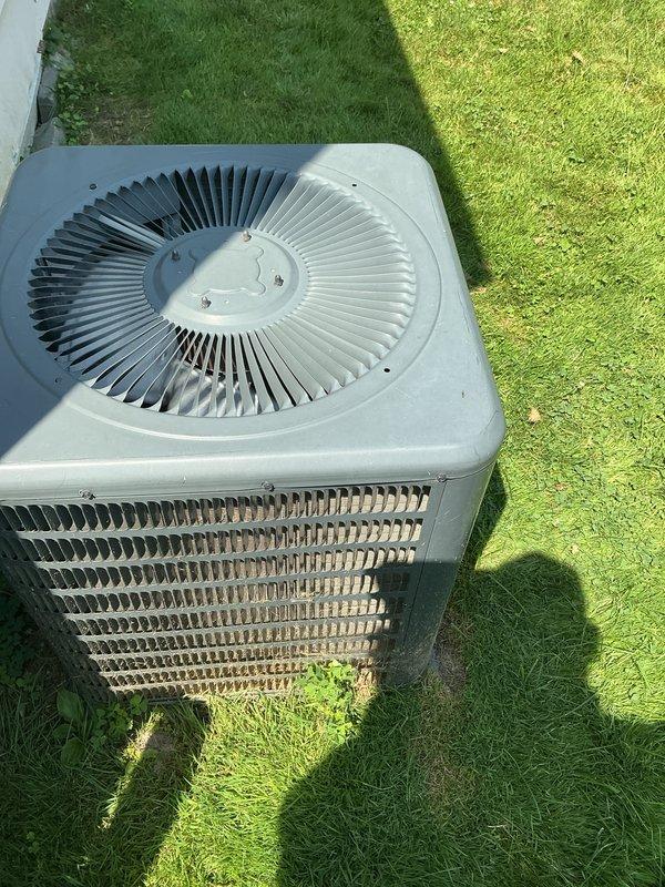 # HVAC Maintenance - Gold AC Inspection

Performed comprehensive Gold-level preventive maintenance inspection on residential outdoor air conditioning condenser unit, approximately eight years old. Upon arrival, unit was accessible on exterior lawn area adjacent to building foundation.

## Inspection and Testing Procedures

Conducted thorough visual inspection of condenser cabinet and housing, verifying structural integrity of metal casing and protective grilles. Examined top-mounted fan assembly with circular blade configuration, confirming proper mounting and secure fastening of fan cover components. Inspected horizontal louver grilles on side panels for damage or obstruction.

Assessed condition of heat exchanger coil fins visible through protective grille, noting accumulation of dirt, debris, and environmental contaminants on copper-colored cooling fins. Documented outdoor weathering and exposure effects on exterior surfaces consistent with regular operational use.

Evaluated conden