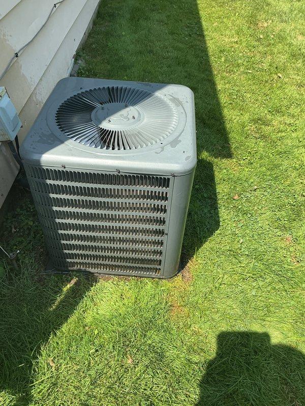 # HVAC Maintenance - Gold AC Inspection

Performed comprehensive Gold-level preventive maintenance inspection on residential outdoor air conditioning condenser unit, approximately eight years old. Upon arrival, unit was accessible on exterior lawn area adjacent to building foundation.

## Inspection and Testing Procedures

Conducted thorough visual inspection of condenser cabinet and housing, verifying structural integrity of metal casing and protective grilles. Examined top-mounted fan assembly with circular blade configuration, confirming proper mounting and secure fastening of fan cover components. Inspected horizontal louver grilles on side panels for damage or obstruction.

Assessed condition of heat exchanger coil fins visible through protective grille, noting accumulation of dirt, debris, and environmental contaminants on copper-colored cooling fins. Documented outdoor weathering and exposure effects on exterior surfaces consistent with regular operational use.

Evaluated conden