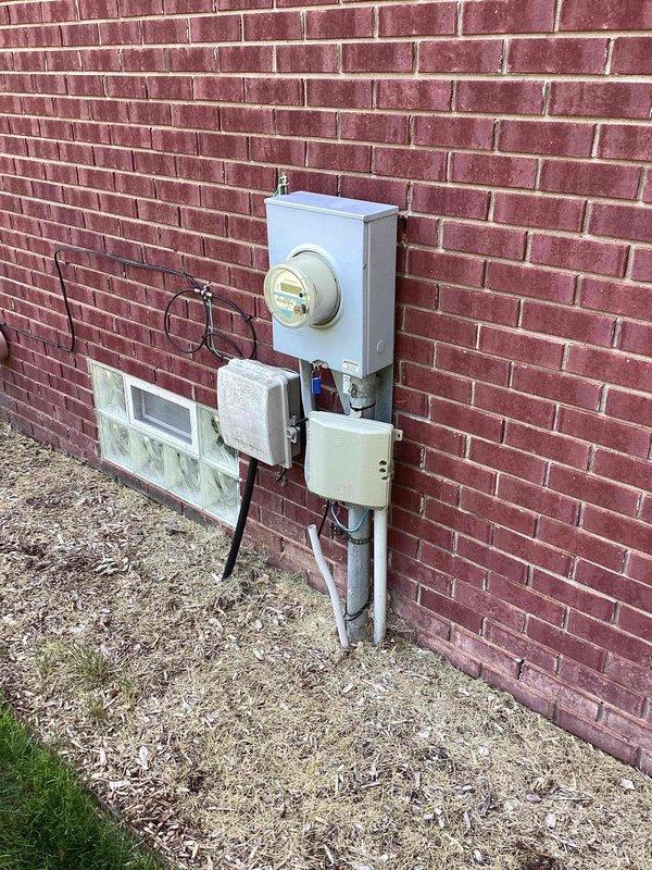 Conducted site evaluation for HVAC system replacement at residential property with exterior-mounted air conditioning condenser unit located on concrete pad adjacent to brick exterior wall. Assessed existing equipment condition, electrical service configuration including meter and disconnect panel, and installation requirements for replacement system. Documented current system specifications, clearances, and accessibility considerations to provide comprehensive equipment replacement estimate.
