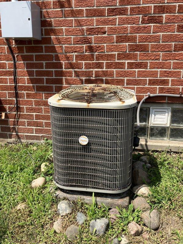Conducted on-site evaluation of existing packaged air conditioning unit located on exterior concrete pad against brick foundation. Assessed current cooling system serving small residential space under 1500 square feet. Documented equipment condition, refrigerant line routing, electrical disconnect configuration, and unit placement for replacement estimate preparation.