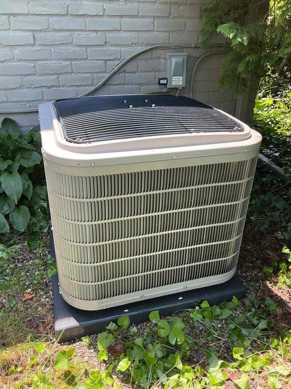 Completed comprehensive Gold AC inspection on a 6-year-old residential air conditioning system. Performed thorough examination of outdoor condenser unit positioned against exterior brick wall, verifying proper clearance from surrounding vegetation and adequate airflow around cabinet. Inspected electrical connections, disconnect box, and conduit routing for code compliance and secure mounting. Evaluated refrigerant line insulation and copper piping condition running along wall to basement air handler location. Checked condenser pad levelness and stability, confirmed fan grille integrity and protective components in place. Verified unit operational status with homeowner present, documenting equipment condition through photographic records. System found operating normally with clean exterior surfaces and intact housing, suitable for continued seasonal use.