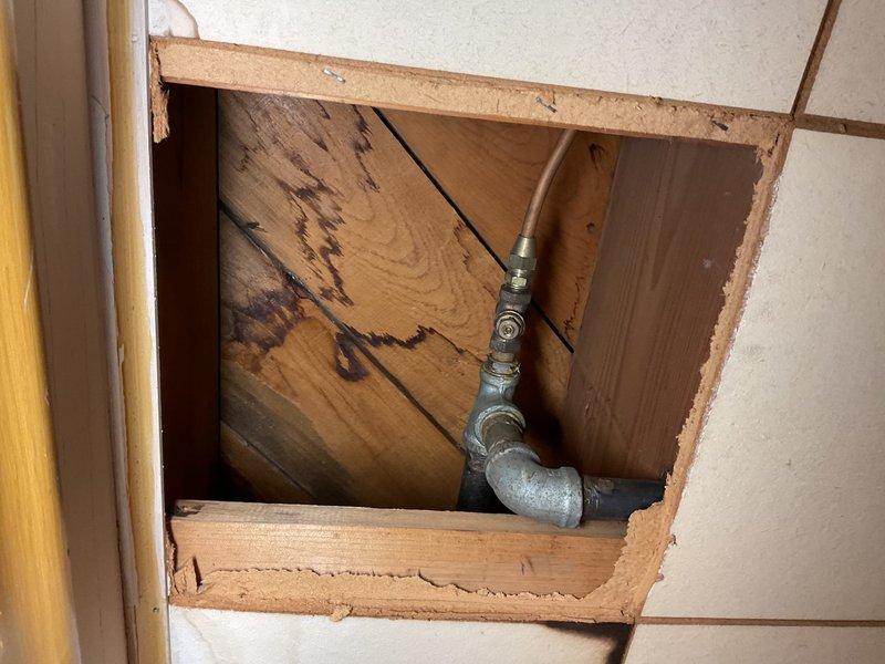 Installed shut-off valves on gas lines serving the dryer and furnace, which were previously hard-piped without individual isolation capability. Created wall access point through tiled surface to reach gas line connections, installed code-compliant ball valves on both appliance supply lines, and restored wall access opening. Work enables safe appliance disconnection for future service or replacement without shutting down entire gas system.