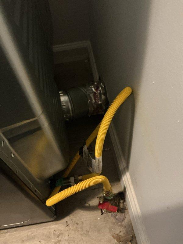 Installed new water heater with complete plumbing connections, including white PVC piping assembly configured in T-shape arrangement with pressure relief valve and flexible supply lines. Connected black discharge pipe extending to floor drain and verified all connections for proper operation and code compliance.