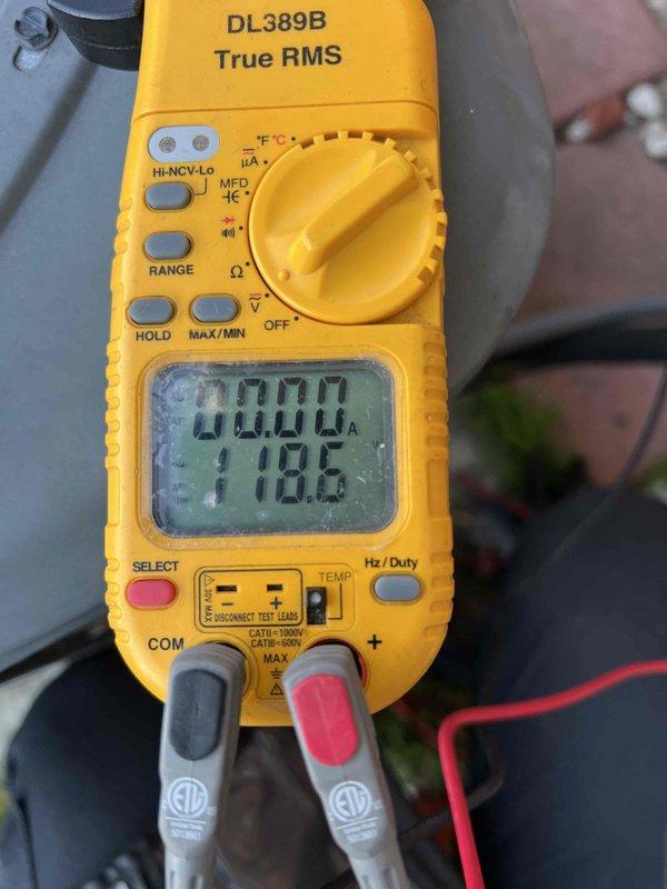 Completed comprehensive Gold AC inspection on 15-year-old residential air conditioning system with outdoor condenser unit located on exterior concrete pad and air handler in basement. Performed multi-point system evaluation including electrical diagnostics with clamp meter recording voltage at 118.6V, visual inspection of condenser unit confirming proper airflow through louvers and fan grille, and verification of refrigerant lines and condensate drainage. Unit found operating within normal parameters with no immediate service needs identified; condenser exterior shows normal weathering consistent with age, concrete pad structurally sound, and all components functioning as designed.