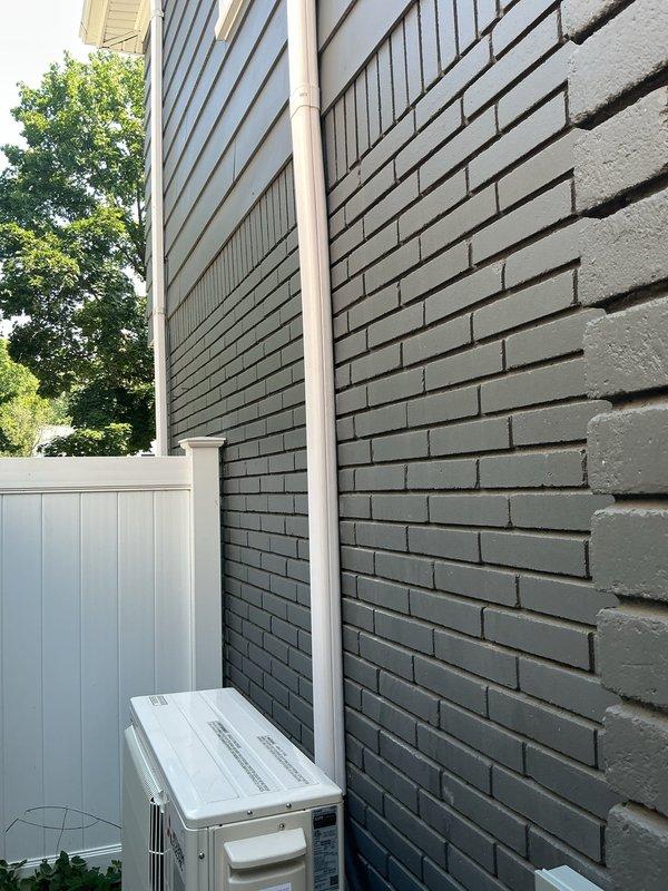 Removed and recycled existing condenser unit and installed a Mitsubishi WX series heat pump system on an elevated stand against exterior brick wall. Ran new refrigerant line set up exterior wall with line hide cover, installed wall-mounted indoor unit with standard handheld controller, and established gravity condensate drainage to side yard. Repurposed existing electrical power with GFI protection in place, mounted outdoor disconnect box, and verified system operation upon completion.