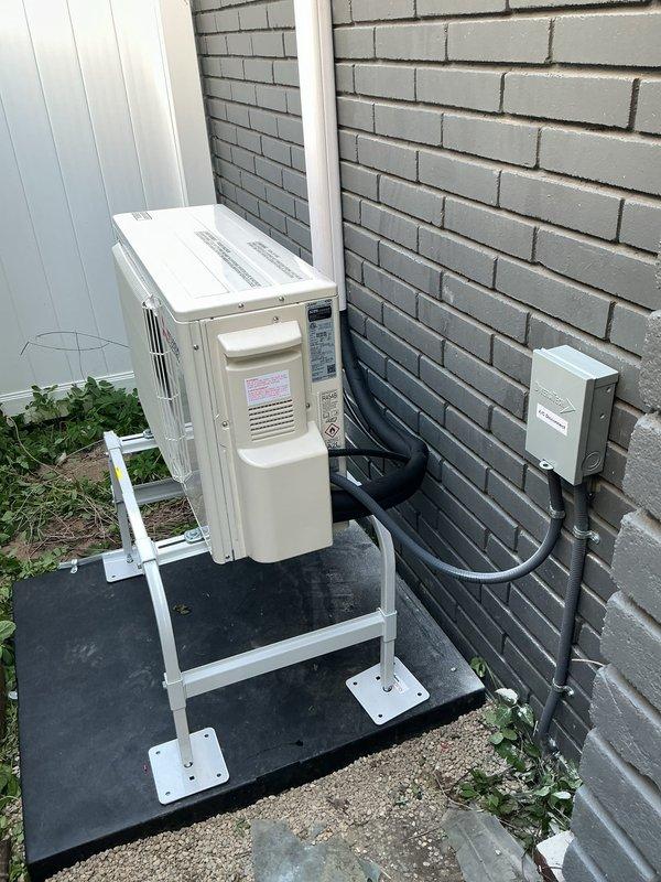 Removed and recycled existing condenser unit and installed a Mitsubishi WX series heat pump system on an elevated stand against exterior brick wall. Ran new refrigerant line set up exterior wall with line hide cover, installed wall-mounted indoor unit with standard handheld controller, and established gravity condensate drainage to side yard. Repurposed existing electrical power with GFI protection in place, mounted outdoor disconnect box, and verified system operation upon completion.