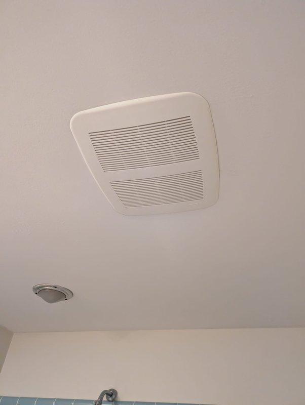 Responded to service call for non-functioning bathroom ceiling exhaust fan. Upon inspection, evaluated the existing rectangular ventilation unit mounted in the bathroom ceiling above the tiled shower area. Assessed fan motor operation, electrical connections, and airflow performance to determine whether repair or replacement was necessary. Documented existing installation configuration including proximity to smoke detector and positioning relative to shower enclosure.
