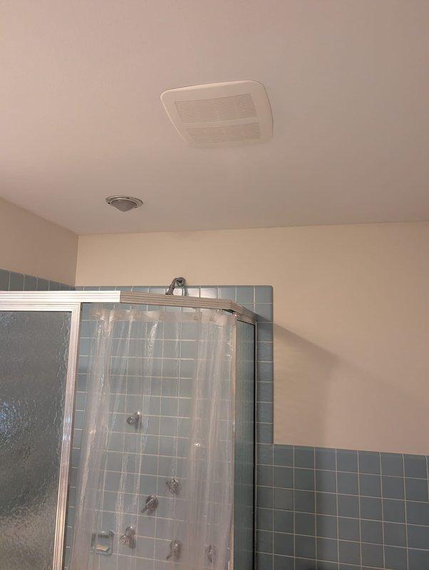 Responded to service call for non-functioning bathroom ceiling exhaust fan. Upon inspection, evaluated the existing rectangular ventilation unit mounted in the bathroom ceiling above the tiled shower area. Assessed fan motor operation, electrical connections, and airflow performance to determine whether repair or replacement was necessary. Documented existing installation configuration including proximity to smoke detector and positioning relative to shower enclosure.