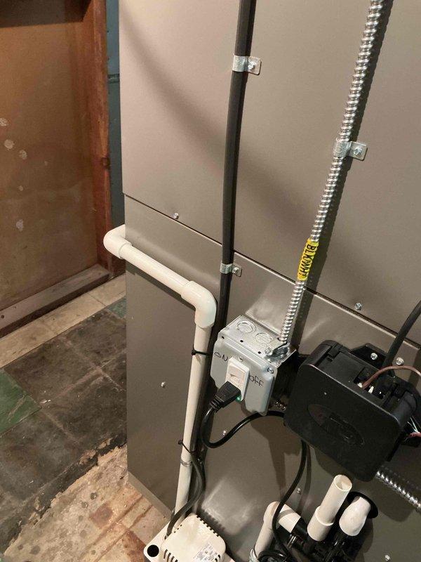 Completed comprehensive Gold AC inspection on a 1-year-old HVAC system with air handler located in basement. System is operational and functioning properly. Performed detailed multi-point inspection including examination of air handler unit, electrical connections, condensate drainage system with PVC piping configuration, flexible metallic conduit runs, and associated mechanical components. Verified proper installation of all system components, checked control box operation with illuminated indicator confirming power supply, inspected mounting and securing of all conduits and piping, and documented system condition through photographic records. All equipment found to be in good working order with no immediate service needs identified.