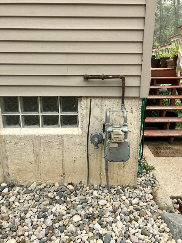 Conducted comprehensive site assessment for new whole home generator installation at residential property. Evaluated existing natural gas meter assembly and connection points on foundation, documented electrical service access via conduit routing near HVAC equipment, and confirmed adequate clearances and foundation support for generator placement. Photographed gas supply infrastructure and electrical pathways to develop installation specifications and equipment requirements for permanent standby generator system.