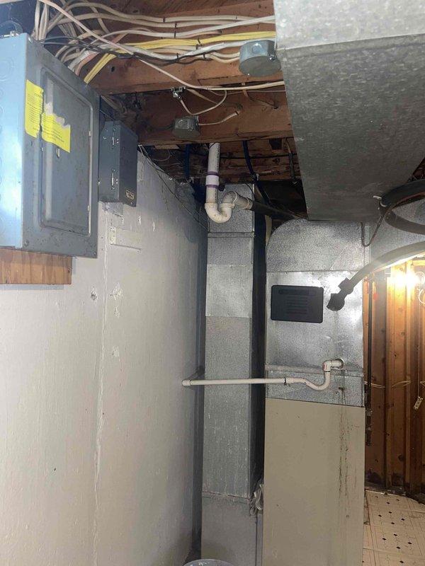 Conducted comprehensive site assessment for complete HVAC system replacement in 1,135 square foot residential property. Evaluated existing basement mechanical room configuration, including current furnace, ductwork, electrical service, and ventilation infrastructure. Documented existing equipment layout, noting gray metal furnace unit with connected PVC venting system, galvanized supply ductwork with visible aging and wear, electrical panel capacity and location, and concrete block foundation conditions. Assessed spatial requirements for new furnace and air conditioning system installation, verifying adequate clearances for equipment placement, service access, and code compliance. Photographed current mechanical room setup to support equipment sizing calculations and installation planning for proposed heating and cooling system upgrade.