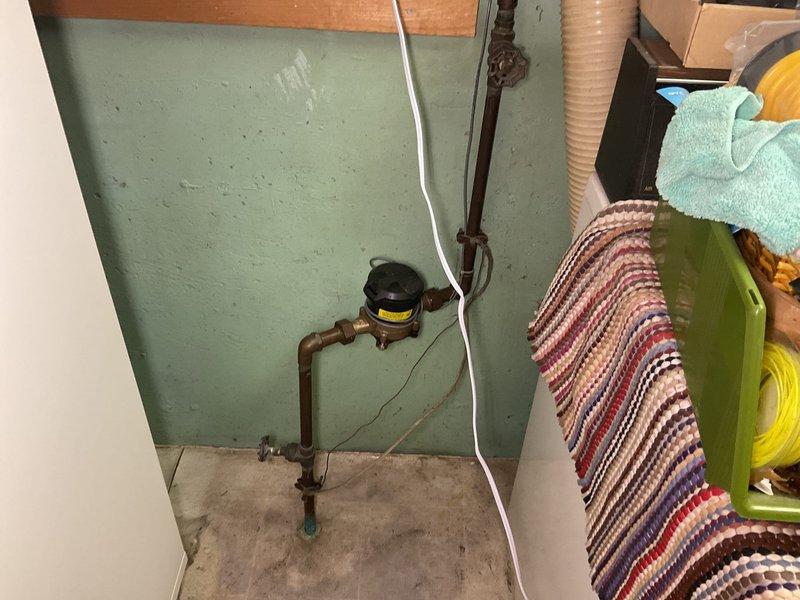 Responded to service call at 60+ year-old residence for evaluation of stiff main water shutoff valve and malfunctioning exterior faucet. Inspected main shutoff valve assembly located near pump in basement utility area, finding aged copper piping with significant patina and compromised valve operation due to internal corrosion and mineral buildup. Valve demonstrated restricted range of motion and failed to achieve complete shutoff position, presenting potential emergency water control concerns. Documented condition of existing plumbing infrastructure including water meter assembly and pipe connections. Assessed exterior faucet for repair feasibility, noting ongoing operational issues. Provided homeowner with professional recommendations regarding main shutoff valve replacement priority given age of installation and current failure to function as designed. Captured photographic documentation of existing conditions for service records and future reference.