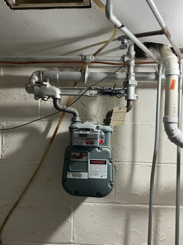 Conducted on-site assessment for Kohler generator installation estimate at residential property. Evaluated existing utility infrastructure including natural gas service with green gas meter, galvanized steel piping, electrical service panel with digital meter, and exterior mounting locations on lap siding. Documented current electrical and gas configurations, photographed utility connections, meter locations, and wall-mounted equipment to develop comprehensive replacement proposal for backup power generation system.