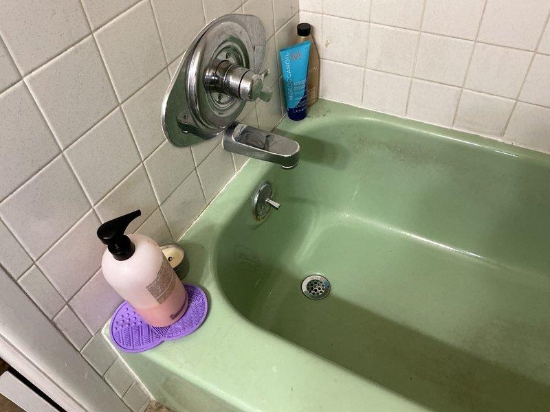 Responded to a slow, intermittent water leak in basement ceiling below bathroom in a 58-year-old home. Conducted thorough assessment of plumbing system, including inspection of vintage mint green bathtub with chrome fixtures and white tile surround. Accessed wall cavity to examine copper supply lines with brass fittings and shut-off valves, noting presence of aged spray foam insulation. Documented conditions with photographs showing plumbing infrastructure, drainage components, and water-damaged ceiling materials. Identified potential leak sources in bathroom plumbing system for further remediation recommendations.