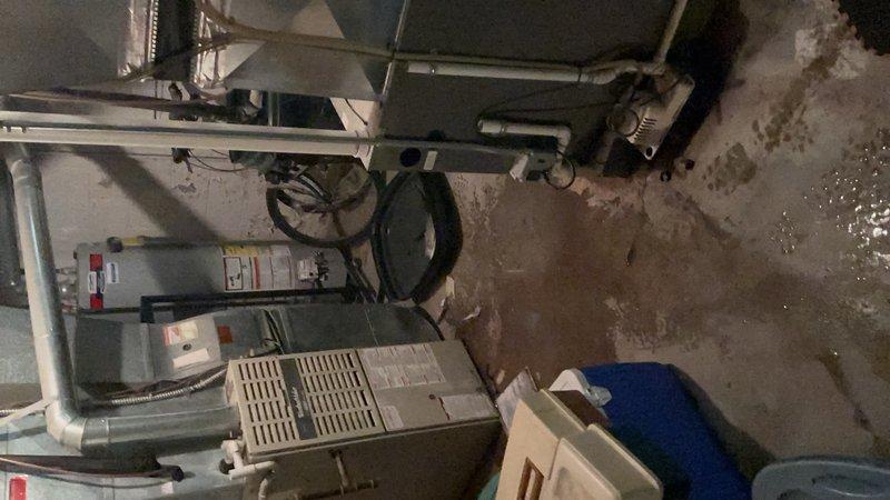 Responded to report of water leaking from bottom of furnace unit located in basement. Upon inspection, identified condensate drainage issue causing water accumulation on concrete floor around base of heating system. Cleared blocked condensate drain line, verified proper drainage flow, and confirmed no additional leaks from heat exchanger or other components. System tested and operating normally with condensate now draining properly through PVC drainage system.