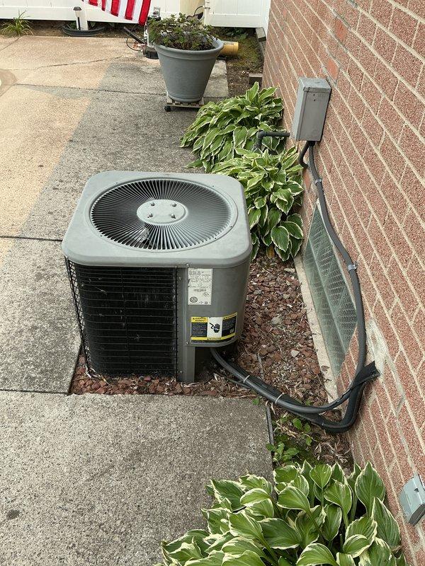 Conducted on-site evaluation and provided replacement estimate for 21-year-old air conditioning system located at rear of residence and furnace unit positioned on east wall of basement. Documented existing equipment configuration, photographed outdoor condensing unit on concrete patio adjacent to brick wall, and identified existing gas line routing near condenser location requiring careful consideration during replacement installation.