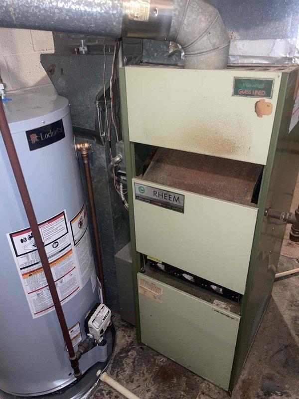 Conducted on-site evaluation for furnace replacement in residential basement. Assessed existing Rheem furnace unit, approximately 50 years old, with pale yellow cabinet showing surface discoloration and wear consistent with age. Documented current system configuration including metal supply ductwork, flexible return ducts, and existing venting arrangement. Evaluated mechanical room layout with water heater proximity and available clearances for new equipment installation. Provided comprehensive replacement quote for modern high-efficiency furnace system to replace aging unit that has exceeded its typical service life expectancy.