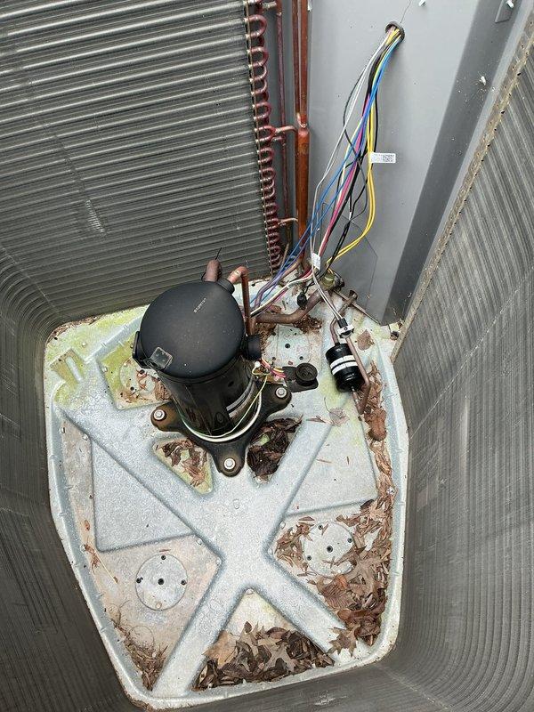 Replaced failed compressor unit on outdoor air conditioning system. Removed old compressor from corroded base pan, installed new compressor with proper mounting and electrical connections. Evacuated system, recharged with appropriate refrigerant to manufacturer specifications, and verified proper operation. Addressed heavily soiled condenser coil and filter panel during service, removing accumulated dirt, debris, and organic matter that had restricted airflow. Noted significant rust corrosion present on unit base pan from water exposure and aging. Secured all electrical wiring with zip ties and ensured proper routing of copper refrigerant lines. System tested and confirmed operational upon completion.
