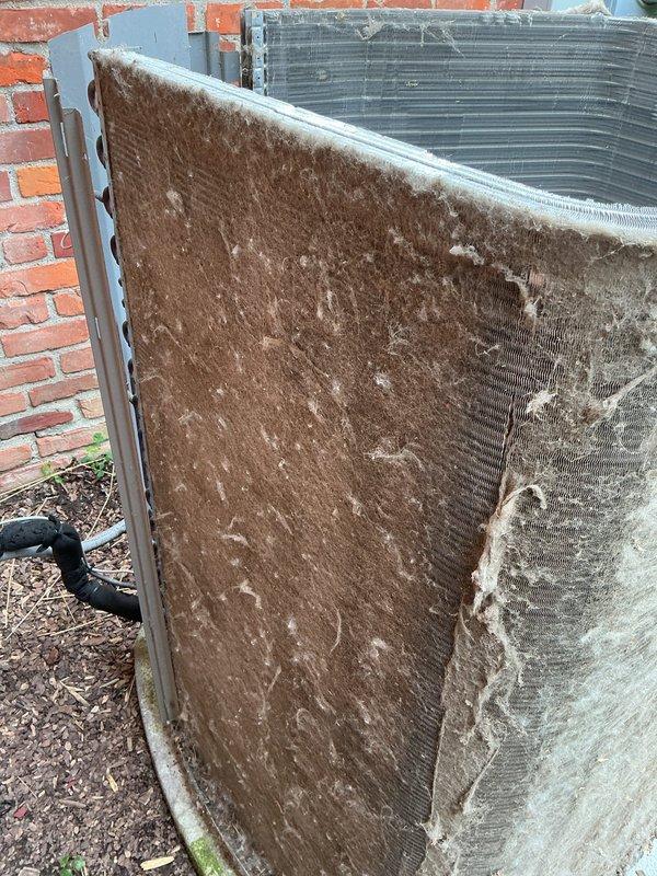 Replaced failed compressor unit on outdoor air conditioning system. Removed old compressor from corroded base pan, installed new compressor with proper mounting and electrical connections. Evacuated system, recharged with appropriate refrigerant to manufacturer specifications, and verified proper operation. Addressed heavily soiled condenser coil and filter panel during service, removing accumulated dirt, debris, and organic matter that had restricted airflow. Noted significant rust corrosion present on unit base pan from water exposure and aging. Secured all electrical wiring with zip ties and ensured proper routing of copper refrigerant lines. System tested and confirmed operational upon completion.