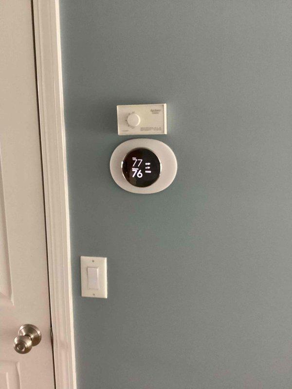 Conducted comprehensive assessment of existing HVAC system for equipment replacement estimate. Documented current thermostat installation and control system configuration, photographing wall-mounted digital thermostat displaying operational status at 77°F and associated HVAC control panel. Evaluated interior equipment location and accessibility to provide accurate replacement recommendations and system specifications.
