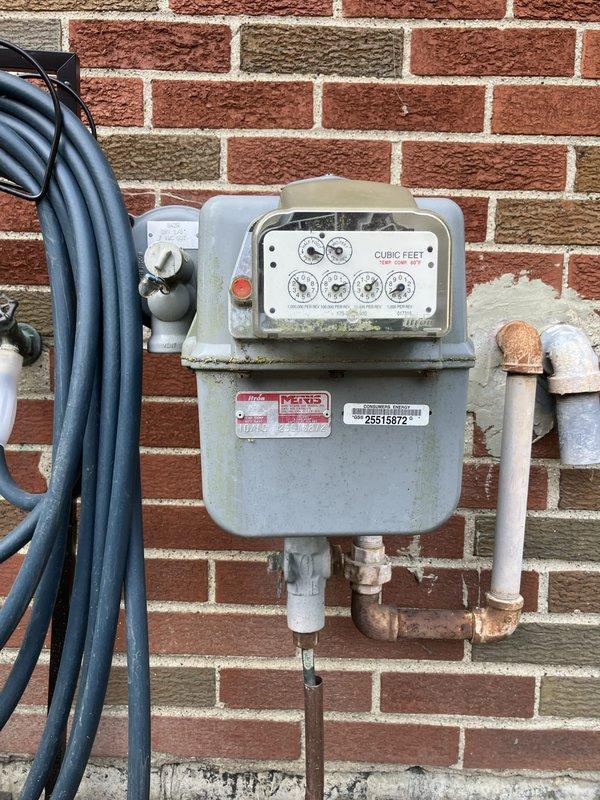 Completed electrical estimate for new whole home generator installation at residential property. Assessed existing natural gas meter and service line capacity on exterior brick wall, evaluated optimal generator placement location in backyard adjacent to existing HVAC equipment and wooden shed, and documented current electrical panel configuration. Identified suitable concrete pad installation area with adequate clearance from structure and utilities, confirmed natural gas availability for generator fuel source, and verified compliance requirements for permanent standby generator system integration with existing electrical service.