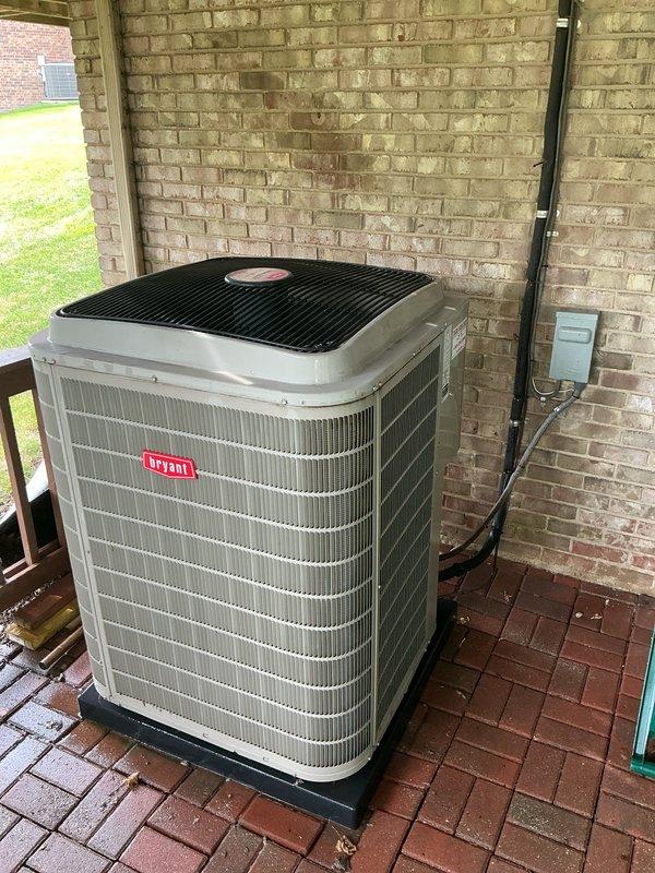Completed comprehensive Gold AC inspection on 13-year-old Bryant air conditioning system with air handler located in basement and condenser unit positioned on exterior patio. Performed full system evaluation including visual inspection of indoor and outdoor components, verified operational status of all equipment, checked refrigerant levels via sight glass gauge, inspected electrical connections and disconnect box, examined condenser coil fins and protective grille, and assessed overall system performance. Unit found to be in operational condition with homeowner confirming proper functionality; documented equipment condition through photographic records showing both indoor furnace components with monitoring gauges and outdoor condenser unit mounted on pad against brick wall with proper clearances maintained.