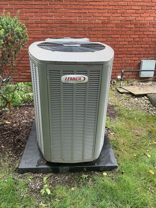 Completed comprehensive Gold AC Inspection on residential property with three Lennox air conditioning units ranging from 2-10 years old. Performed thorough multi-point inspection of outdoor condensing units positioned against exterior brick wall, verified proper operation of all equipment, examined refrigerant line insulation and connections, assessed unit placement and drainage on concrete pads, and documented equipment condition through photographic records. All systems confirmed operational with air handler/coil located in basement area.