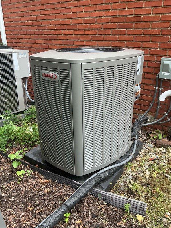 Completed comprehensive Gold AC Inspection on residential property with three Lennox air conditioning units ranging from 2-10 years old. Performed thorough multi-point inspection of outdoor condensing units positioned against exterior brick wall, verified proper operation of all equipment, examined refrigerant line insulation and connections, assessed unit placement and drainage on concrete pads, and documented equipment condition through photographic records. All systems confirmed operational with air handler/coil located in basement area.
