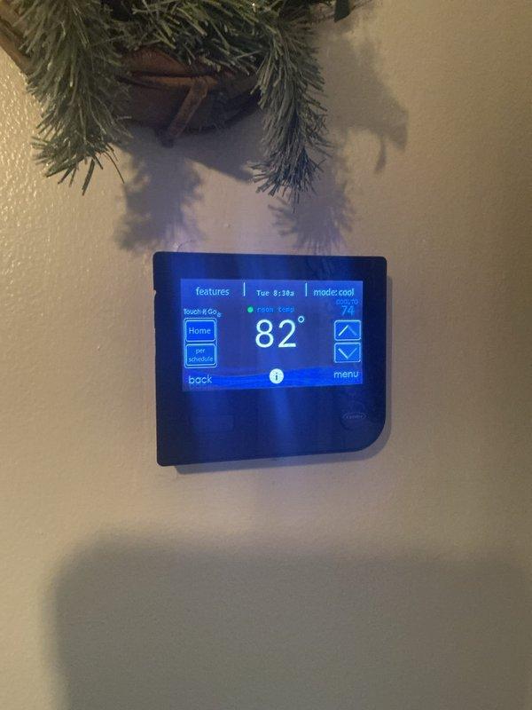 Responded to cooling complaint where indoor temperature was fluctuating between 70s and 80 degrees. Upon arrival, inspected outdoor condenser unit located on right side of residence and evaluated thermostat showing 82 degrees in cooling mode. Performed diagnostic assessment of approximately one-year-old system to determine cause of inadequate cooling performance. Documented equipment condition and thermostat operation with photos for service records.