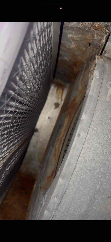 Responded to no-cooling complaint on 20+ year old forced air system. Upon arrival, found furnace blower motor humming but failing to start and outdoor condensing unit only operating when contactor manually engaged. Confirmed customer had previously replaced both indoor blower capacitor and outdoor unit capacitor without resolving the issue.

Performed diagnostic testing on blower motor and determined motor windings had failed, preventing startup despite adequate capacitance. Inspected outdoor unit and found contactor contacts severely pitted and worn, preventing proper closure and unit operation. Documented extensive rust and corrosion on outdoor unit cabinet and indoor air handler base, indicating prolonged moisture exposure and advanced system deterioration. 

Advised customer that both blower motor replacement and outdoor contactor replacement would be required as minimum repairs, but given the age of equipment (20+ years), extensive corrosion visible throughout system components, a