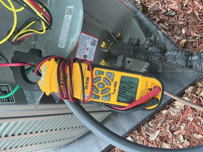 Completed comprehensive Gold AC Inspection on 1-year-old outdoor air conditioning unit located behind residence. Performed full system diagnostics including electrical measurements using digital clamp meter, recording amperage readings of 282.2A and 71.1A to verify proper compressor and fan motor operation within manufacturer specifications. Conducted visual inspection of condenser unit, confirming all components in excellent condition with clean coils, secure panels, intact protective grilles, and proper clearances from surrounding landscaping. Verified refrigerant lines properly insulated, electrical connections secure, and all manufacturer labels intact. Unit operating efficiently with no issues identified during routine maintenance check. Photographic documentation captured for service records. System ready for continued operation through cooling season.