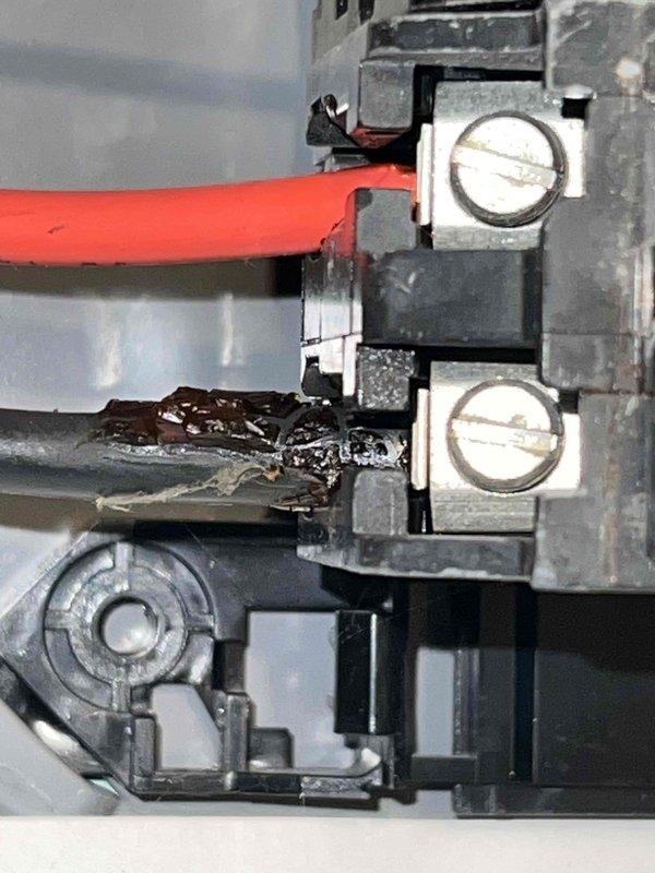 Responded to no cooling call on 16-year-old residential air conditioning system. Upon inspection, discovered severe thermal damage to wiring at outdoor unit's circuit breaker connection. Gray wire insulation was severely burned, melted, and charred with exposed conductor, indicating dangerous electrical failure and fire hazard. The 10-amp Square D breaker showed heavy dust accumulation and signs of extended service life. Documented electrical damage with photographs showing compromised wire integrity at terminal block. System was inoperable due to failed electrical connection preventing power delivery to compressor. Recommended immediate electrical repairs to restore safe operation and prevent potential fire risk.