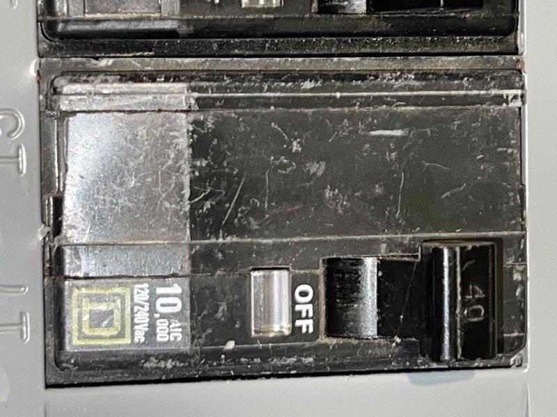 Responded to no cooling call on 16-year-old residential air conditioning system. Upon inspection, discovered severe thermal damage to wiring at outdoor unit's circuit breaker connection. Gray wire insulation was severely burned, melted, and charred with exposed conductor, indicating dangerous electrical failure and fire hazard. The 10-amp Square D breaker showed heavy dust accumulation and signs of extended service life. Documented electrical damage with photographs showing compromised wire integrity at terminal block. System was inoperable due to failed electrical connection preventing power delivery to compressor. Recommended immediate electrical repairs to restore safe operation and prevent potential fire risk.