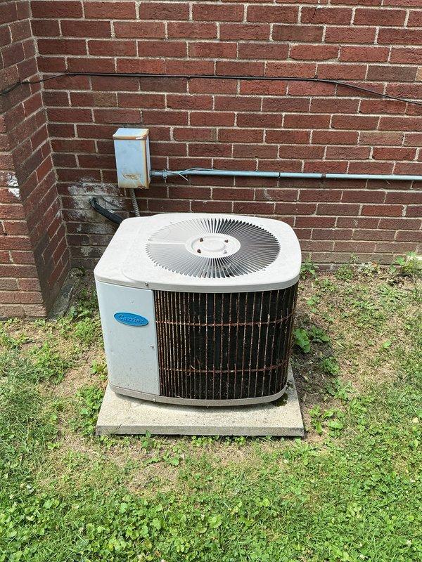 Responded to service call for non-operational air conditioning system, approximately 6 years old, with equipment located in basement. Performed comprehensive assessment of Carrier brand outdoor condensing unit positioned on concrete pad against building exterior. Evaluated complete system including electrical disconnect, refrigerant lines, and conduit connections between outdoor unit and interior components. Provided detailed estimate for complete HVAC system replacement due to failure of existing equipment to power on or operate.