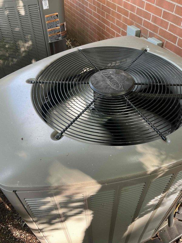 Completed comprehensive Gold AC Inspection on two 1-year-old outdoor condenser units positioned on concrete pads against brick exterior wall. Performed full system evaluation including visual inspection of both units, verified proper fan operation and protective grille integrity, checked refrigerant levels, inspected electrical connections and components, cleaned debris from fan areas and top surfaces, examined condenser coils through louvered panels for airflow obstruction, tested capacitors and contactors, verified proper drainage, and confirmed both systems operating within manufacturer specifications. Both units showed normal weathering consistent with outdoor installation and age, with minor dust accumulation addressed during service. All components functioning properly with no deficiencies noted.