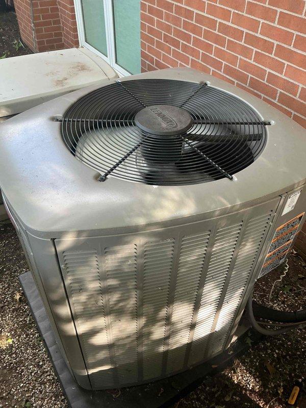 Completed comprehensive Gold AC Inspection on two 1-year-old outdoor condenser units positioned on concrete pads against brick exterior wall. Performed full system evaluation including visual inspection of both units, verified proper fan operation and protective grille integrity, checked refrigerant levels, inspected electrical connections and components, cleaned debris from fan areas and top surfaces, examined condenser coils through louvered panels for airflow obstruction, tested capacitors and contactors, verified proper drainage, and confirmed both systems operating within manufacturer specifications. Both units showed normal weathering consistent with outdoor installation and age, with minor dust accumulation addressed during service. All components functioning properly with no deficiencies noted.