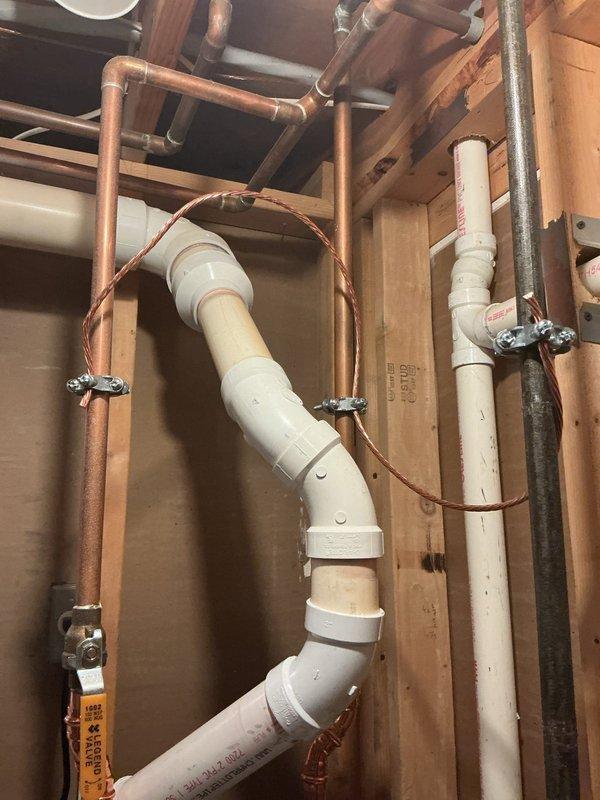 Responded to a violation notice regarding bonded hot water heater installation. Upon arrival, inspected exposed plumbing infrastructure within wall cavity and basement utility area. Documented existing plumbing configuration including white PVC drainage assembly with multiple elbows and joints running vertically through framing, copper supply lines with chrome shut-off valves, and galvanized steel piping. Verified sump pump basin installation with associated PVC discharge piping system. Photographed all plumbing connections, valve locations, and mechanical chase conditions for compliance documentation and warranty record purposes.